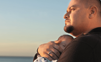 Patient mit paroxysmaler nächtlicher Hämoglobinurie (PNH) hält einen Säugling im Arm