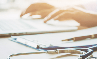 Ärztin arbeitet am Laptop mit Stethoskop im Vordergrund