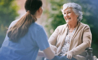 Fröhliche alte Frau spricht mit Pflegerin