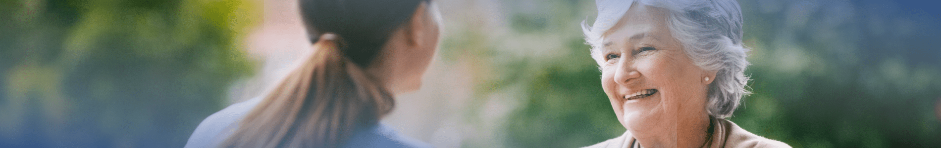 Lächelnde Patientin mit AL-Amyloidose wird von einer Pflegerin unterstützt