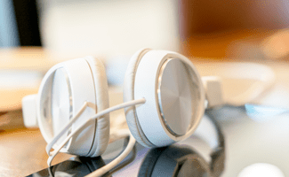 Weiße Kopfhörer auf einem Tisch, symbolisch für den Alexion Podcast 